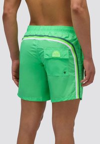 Pantaloni da bagno verdi con una texture leggera e lucida, caratterizzati da strisce bianche e blu navy, una vita regolabile e una tasca posteriore.