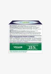 Moisturizing cream container featuring a blue lid, white body, and green accents. Text in multiple languages details application and ingredients.