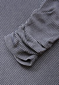 Marineblau-weiß gestrefter Stoff mit einer strukturierten Oberfläche, der geraffte Falten aufweist und eine sanfte Dehnbarkeit sowie eine glatte Oberfläche zeigt.