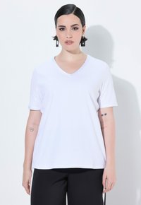 T-shirt bianca a maniche corte con scollo a V, realizzata in un tessuto liscio e leggero. Presenta una vestibilità rilassata e orlo diritto in vita.