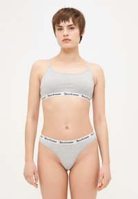 Pilkas medvilninis liemenėlė ir kelnaitės rinkinys su plonomis petnešėlėmis. Juostos turi juodą "Juicy Couture" logotipą ant balto fono. Lygus paviršius.