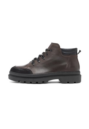 Stivaletto alla caviglia in pelle marrone scuro con colletto imbottito nero, suola in gomma nera e occhielli metallici per i lacci, mostrato in profilo laterale.