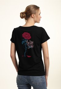 Camiseta de algodón negra con un gran gráfico de una rosa roja, con tallos verdes y acentos azules, junto con el texto "La Bella y la Bestia" en blanco.