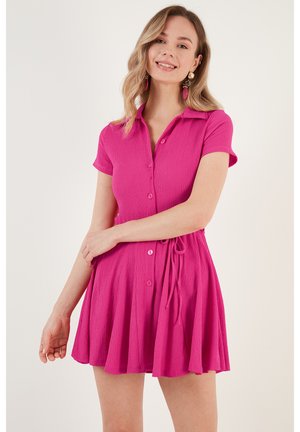 Short pink button-up dress with short sleeves, textured fabric, A-line shape, and a drawstring waist. Features a collar and matching buttons.