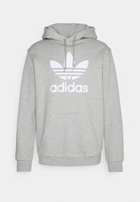 Grå huoodtröja med en vit Adidas-logotyp med ett bladdesign, snören och en framficka.