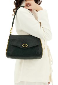 Borsa a tracolla in pelle verde scuro con patta frontale, dettagli hardware dorati e borchie arrotondate lungo il bordo. Dotata di tracolla.