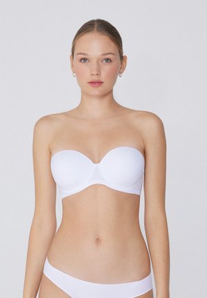 Witte strapless beha met gladde stof, voorgevormde cups en subtiele naden. Gecombineerd met bijpassende witte slipjes. Zachte textuur en naadloos ontwerp.