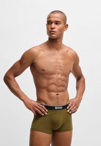 Olivgrüne Boxershorts mit einem schwarzen Bund, auf dem das "BOSS"-Logo zu sehen ist. Glatter Stoff, taillierte Passform und mittellanger Schnitt, der eine nahtlose Optik bietet.