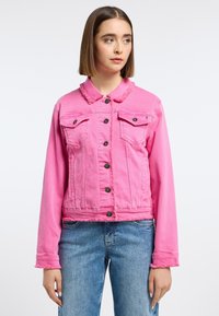 Chaqueta de mezclilla rosa con cuello y dobladillo deshilachados, cuenta con dos bolsillos en el pecho, botones negros y mangas largas, combinada con jeans azules.