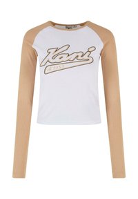 Hvit og beige langermet topp med ribbestruktur, med "Kani est. 1989" logo i beigeskrift over brystet og kontrasterende ermer.