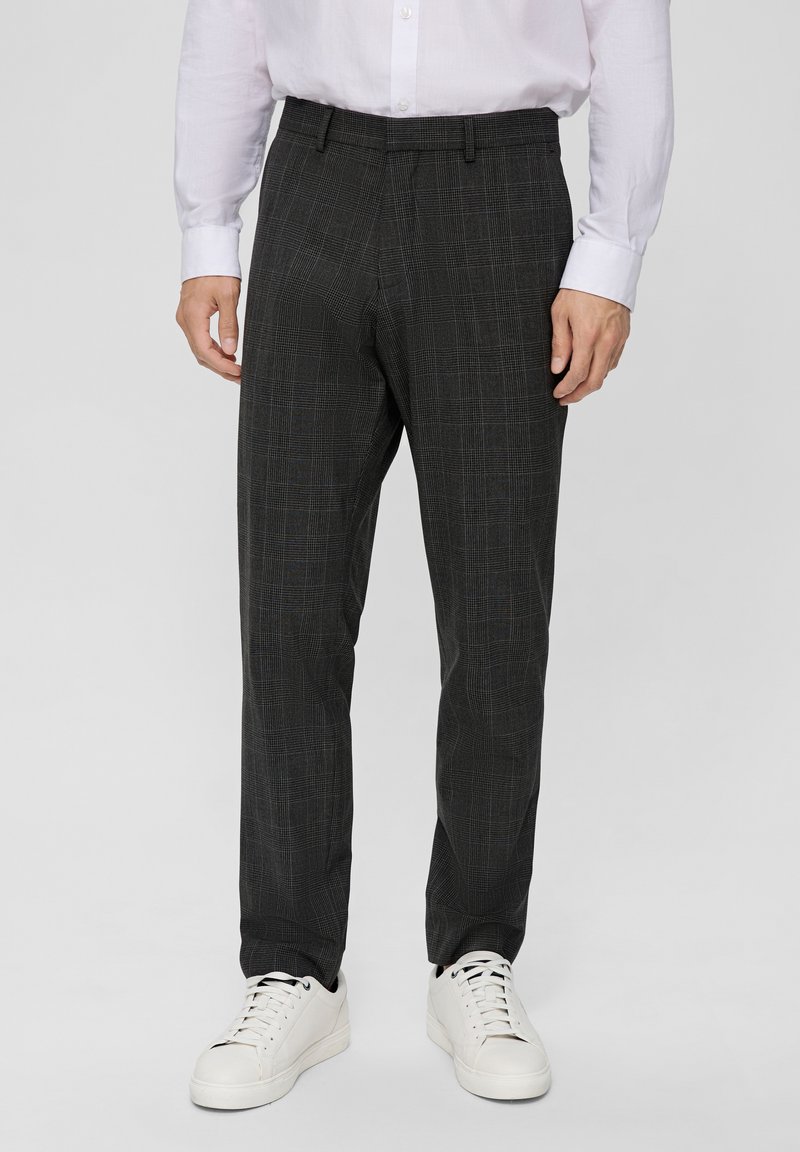 Pantalon gris à motifs avec un design à carreaux, fabriqué en tissu tissé, associé à des baskets blanches. Coupe ajustée avec des coutures repassées.
