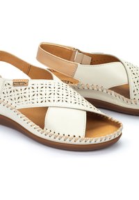 Weiße Ledersandalen mit ausgeschnittenem Blumenmuster, tanfarbenen Akzenten und gestepptem Sohle. Verstellbarer Riemen für einen sicheren Sitz. Flache, offene Zehenform.