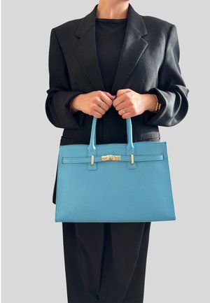 Niebieska skórzana torebka o strukturalnym kształcie, z górnymi uchwytami i srebrnymi akcentami metalowymi. Powierzchnia ma gładką teksturę i minimalne detale.