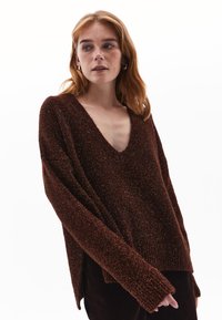 Maglione marrone a collo a V con maniche lunghe e ampie, realizzato in tessuto testurizzato e lucido. Presenta una vestibilità rilassata e polsini e orlo a costine.