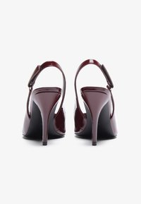 Sandali con tacco alto in pelle verniciata bordeaux, con cinturino slingback e punte appuntite, caratterizzati da un design elegante e una texture liscia.