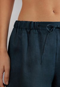 Dunkelblaue Leinen-Shorts mit elastischem Bund und Kordelzug. Sanfte Textur, lockerer Sitz und minimalistisches Design. Keine sichtbaren Taschen.
