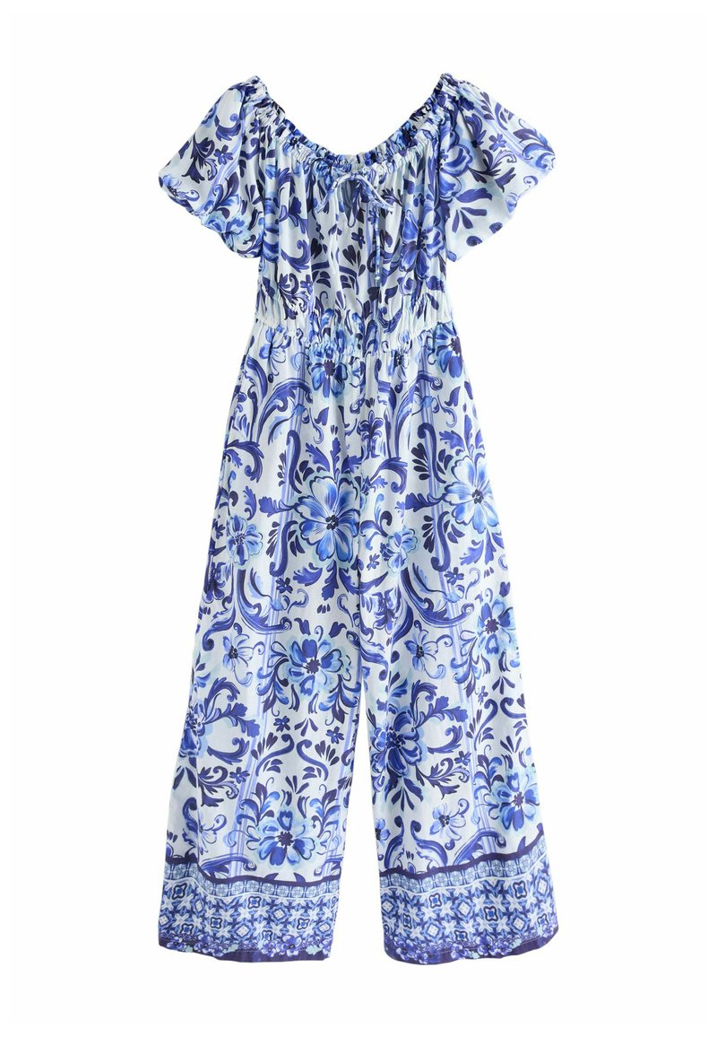 Blomstermønstrets jumpsuit i lyseblå og marineblå. Har korte puffærmer, elastisk talje og brede ben med en dekorativ kant.