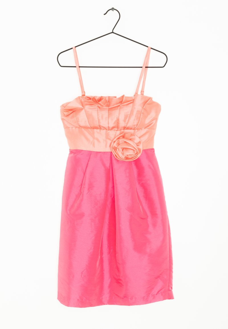 Robe bustier rose en satin avec un corsage froncé, une grande rose en tissu à la taille, suspendue sur un cintre en métal noir sur fond blanc.