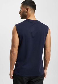 Mørkeblå ermeløs t-skjorte laget av myk bomull, med klassisk rund hals og en glatt tekstur, med rett kant og minimalistisk design.