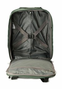 Interno di uno zaino verde a guscio morbido con cinghie incrociate, fodera grigia, diversi scomparti e un tessuto leggero e strutturato.