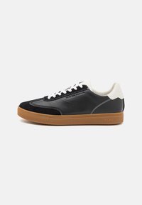Black leather and suede sneaker with white accents, flat laces, and a gum rubber sole. Features contrasting stitching and embossed branding.
