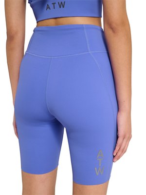 Kobieta ubrana w niebieskie krótkie spodenki kolarskie z wysokim stanem oraz dopasowany krótki top z logo "ATW", widoczna od tyłu od talii do połowy uda.