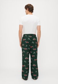 Zöld pizsama nadrág, piros autók és fák mintázattal. Puha anyagból készült, laza szabású és rugalmas derékkal.