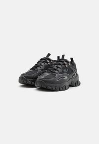 Baskets de sport noires avec un dessus en maille texturée, une semelle épaisse et rembourrée, un système de laçage bien visible et un détail de logo sur le côté.