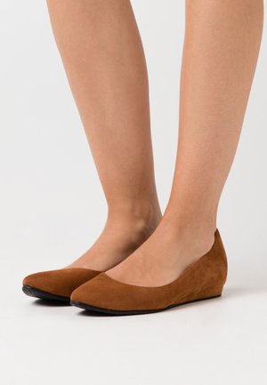 Ballerines en suédine marron à semelle compensée avec un bout pointu et une texture lisse, dotées d'un petit talon compensé pour un confort accru.