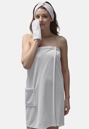 Răwrap din prosop alb din terrycloth cu un buzunar lateral, asociat cu o bandă de cap și un mănușă asortate, evidențiind o textură moale și un design simplu.