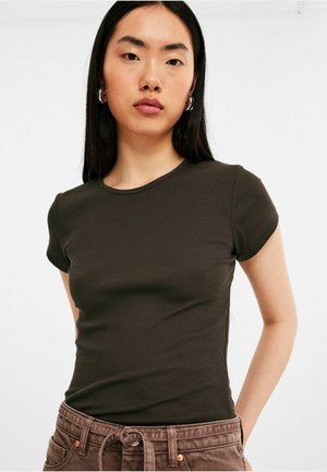 Donkergroen, aansluitend t-shirt met korte mouwen en een ribbeltextuur. De halslijn is rond, en de stof lijkt zacht en glad te zijn.