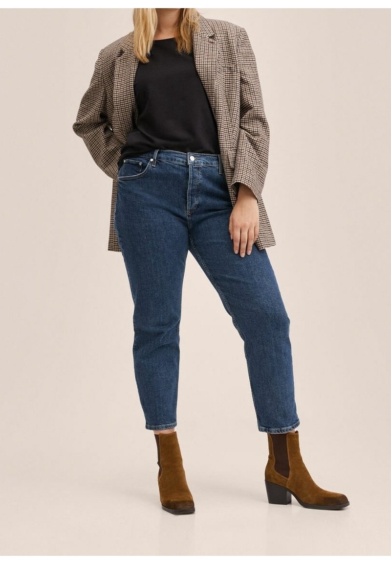 Jean taille haute bleu foncé à coupe droite, associé à un haut noir ajusté et un blazer marron à motifs. Des bottines marron complètent la tenue.