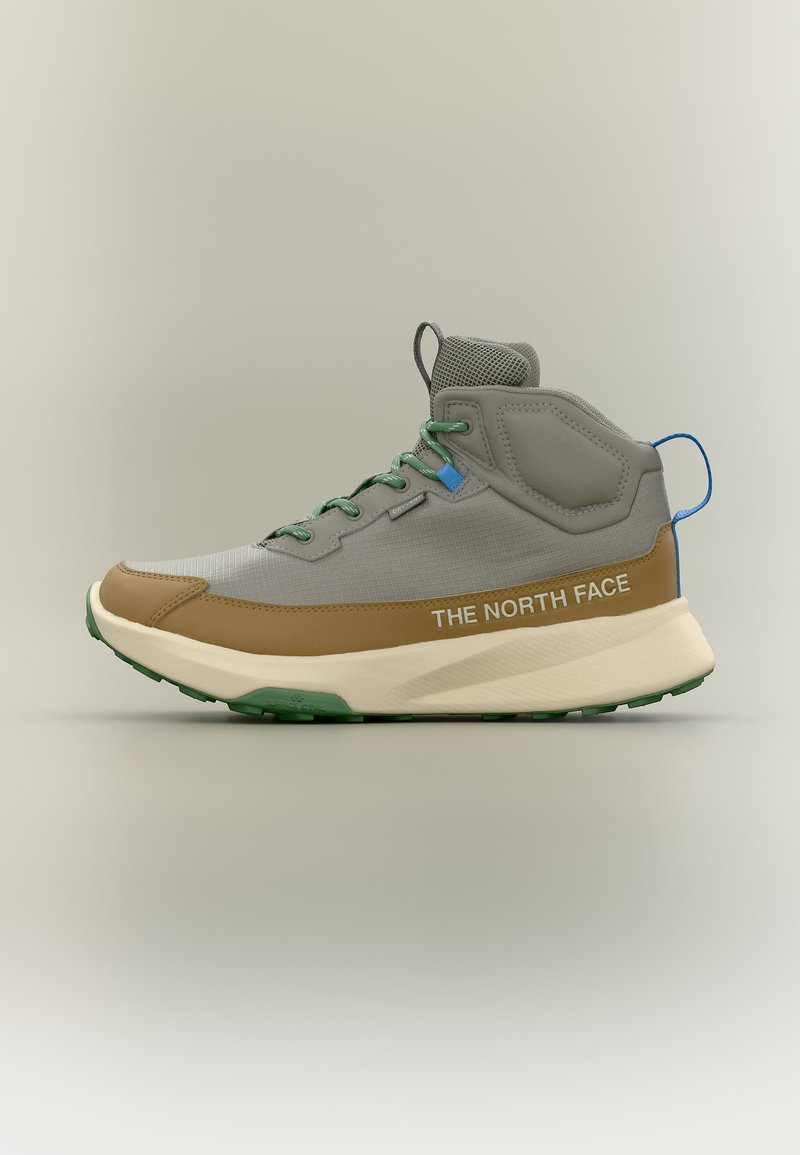 Ανοιχτό γκρι και καφέ παπούτσι πεζοπορίας μέσης-ύψους με πράσινα κορδόνια, ανάγλυφη μπεζ σόλα, μπλε τριχιά τράβηγμα και κείμενο "THE NORTH FACE" στο πλάι.