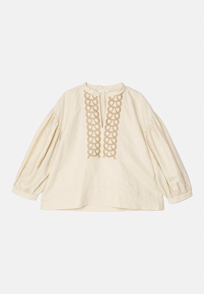 Blouse beige à manches longues avec des manches froncées et des broderies en boucle décoratives le long de l'encolure devant.