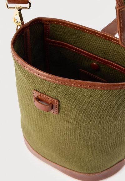 Τσάντα κάδου από ύφασμα ελιάς με καφέ δερμάτινες λεπτομέρειες, εσωτερική τσέπη και χρυσό μεταλλικό κούμπωμα στη αποσπώμενη ιμαντα ώμου.