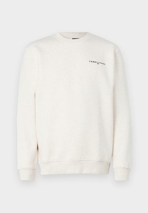 Hellä beige collegepaita pehmeästä kankaasta, jossa on pyöreä kaula-aukko ja ribbikuvioidut hihansuiden. Rinnassa mustalla väriä "TOMMY JEANS" -logo.