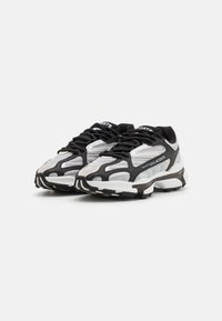 Baskets de sport noir et blanc avec dessus en maille et synthétique, bout rond, accents texturés et semelle épaisse avec motif de traction.