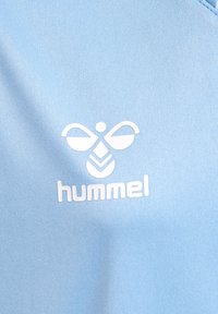 Ljust blått tyg med en vit logotyp bestående av symmetriska former och varumärket "hummel" under den.