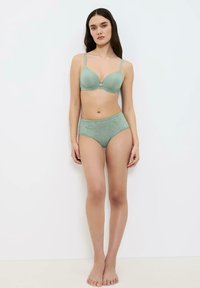Sujetador verde con copas moldeadas y tirantes ajustables, combinado con bragas de talle alto decoradas con encaje en el mismo color y textura suave.