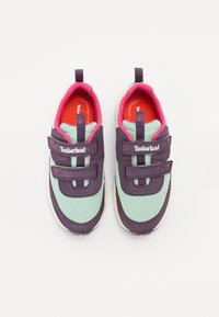 Lilla og myntefargede mesh-sneakers har to borrelås-stropper, en polstret rosa krage og en kontrasterende oransje såle med Timberland-merket.