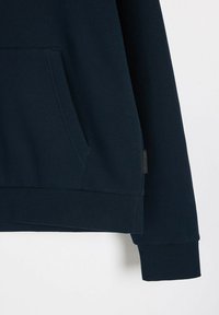 Granatowa bluza z kangurzą kieszenią, ribbowanymi mankietami i dołem. Wykonana z miękkiego materiału, z małą metką z boku.