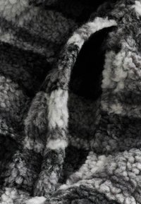 Strukturierter, wolliger Stoff in Grautönen und Weiß, mit einer flauschigen, samtigen Oberfläche, die ein karierte Muster und eine weiche, dicke Webart aufweist.