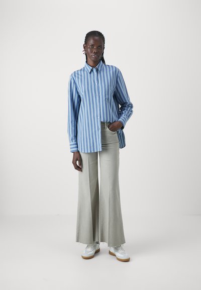Blau-weiß gestreiftes Hemd mit Knöpfen, lockerer Schnitt, lange Ärmel. Helle graue, weit geschnittene Hose, weiße Sneakers. Minimalistisches Design.