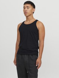 Un débardeur noir en coton avec un col rond, présentant une coupe ajustée et une texture lisse, associé à un pantalon en lin noir ample.