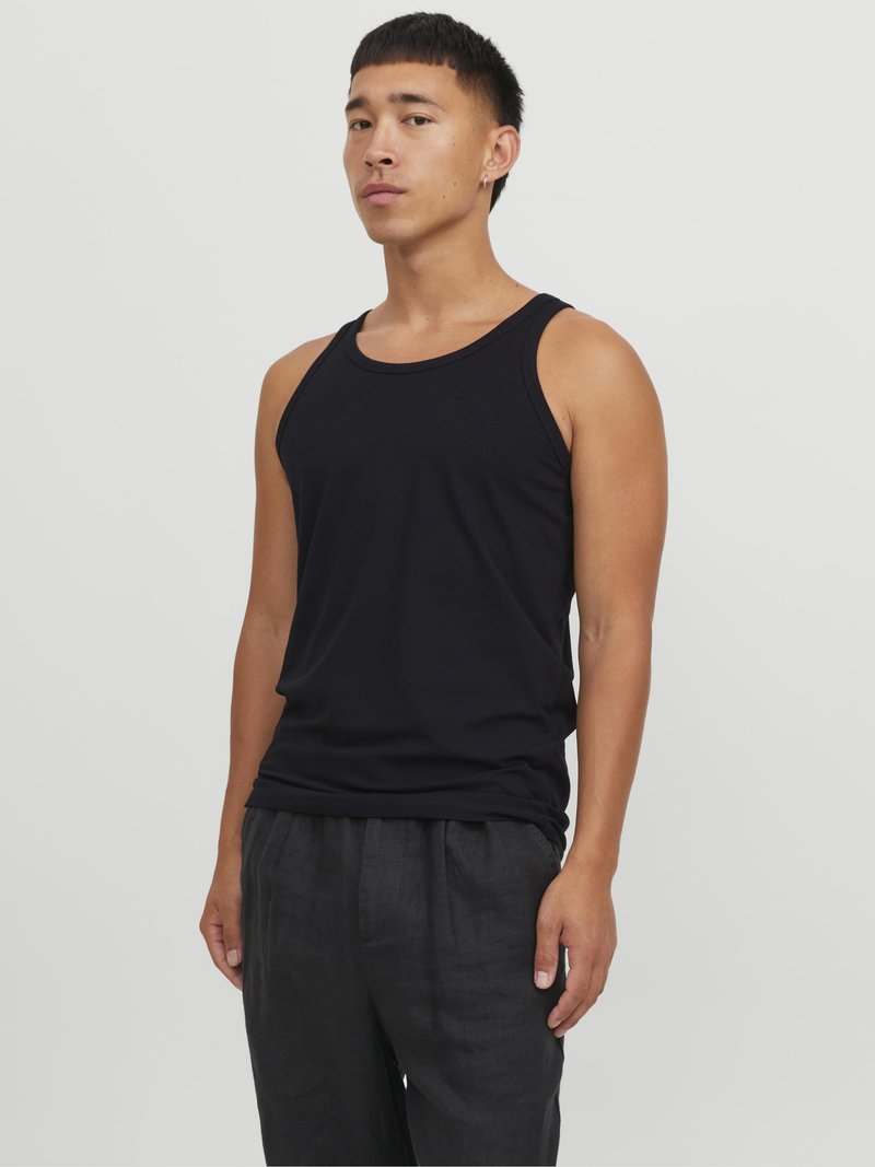 Un débardeur noir en coton avec un col rond, présentant une coupe ajustée et une texture lisse, associé à un pantalon en lin noir ample.