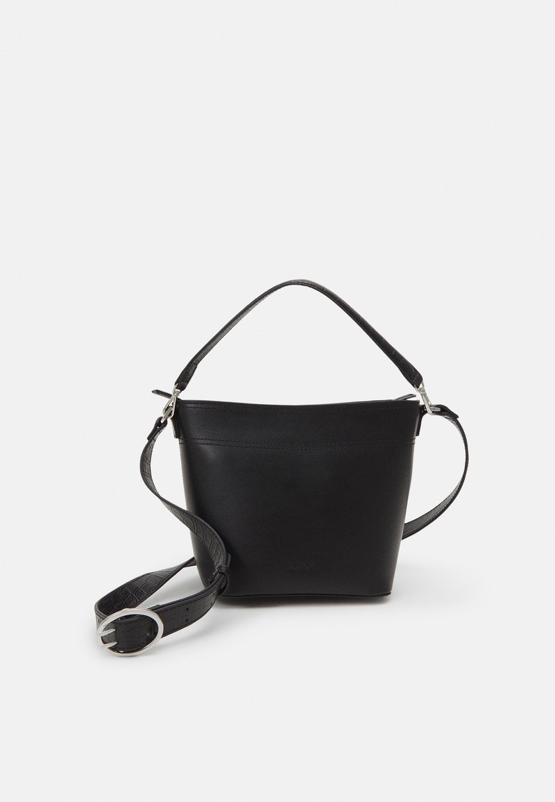 Borsa a secchiello in pelle nera con manico corto e tracolla regolabile con fibbia argentata su sfondo bianco.