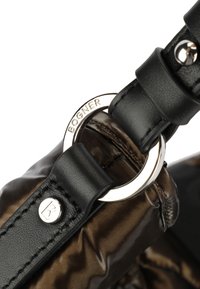 Zwarte leren band bevestigd aan een glanzende bruine stoffen tas. Kenmerkt een zilveren ronde hardware-accent met de naam "BOGNER." Soepele textuur.