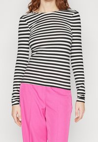 Långärmad tröja med svart och vit horisontell rand, med rund halsringning och matchad med klara rosa byxor.