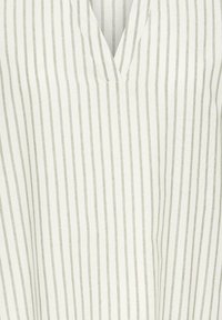 Tissu blanc avec de fines rayures grises verticales et un col en V.