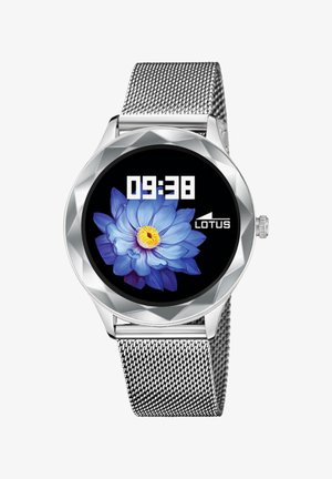 Srebrni pametni sat s okruglom, fasetiranom kućištem. Ima digitalni prikaz s cvjetnim dizajnom, koji prikazuje vrijeme 09:38 i marku "LOTUS." Remen od mrežice.